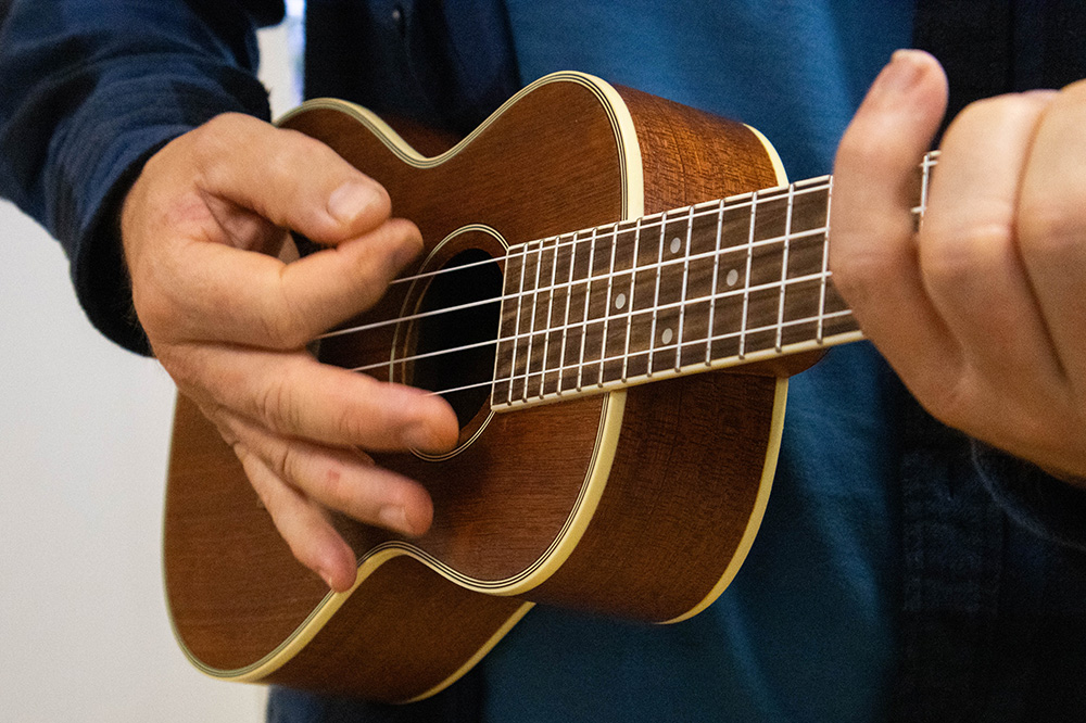 Fingrar klimprar på ein ukulele. Fotografert på nært hald.
