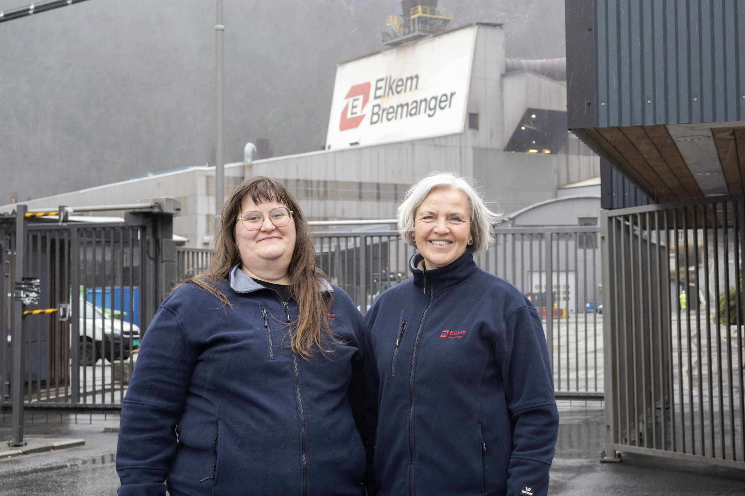 To kvinner står framfor ein fabrikk.