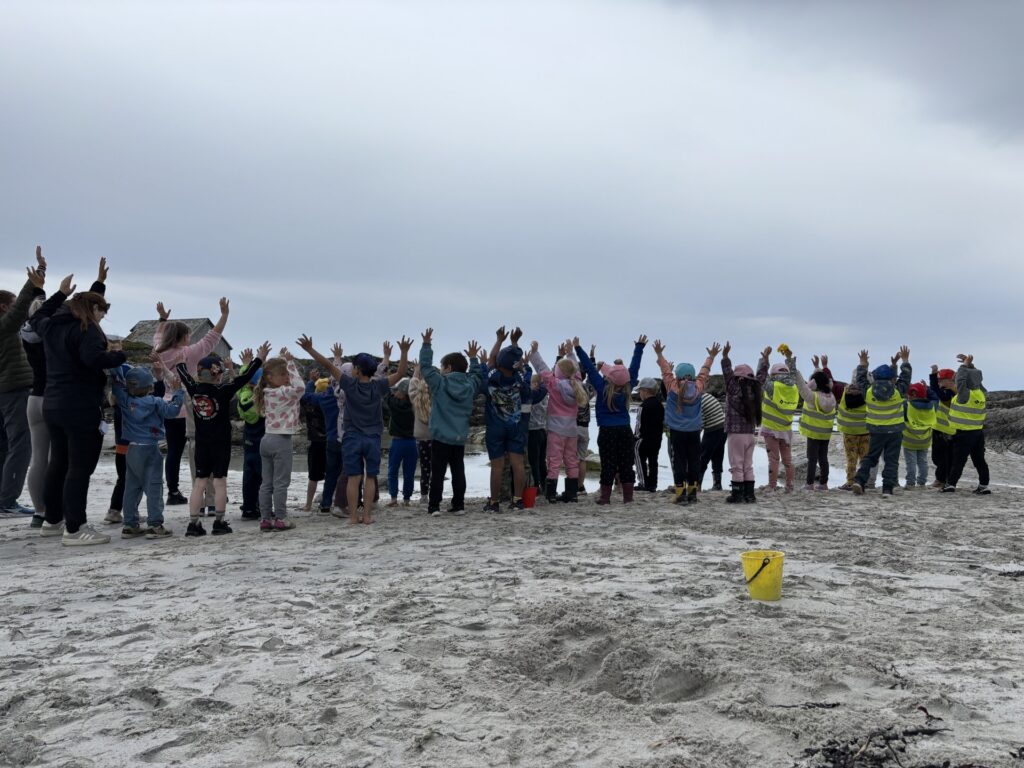 Fotografi av ei gruppe med barn som står med ryggen til og hiv hendene opp i været. 